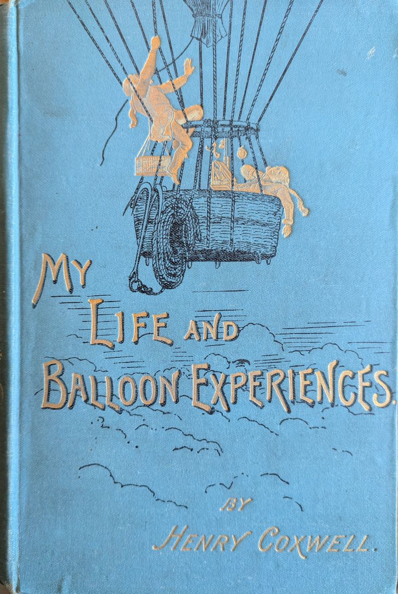 Picture of blue book cover showing two men drawn in gilt in a dark blue drawing of a gas balloon basket at high altitude. Title and author is in gilt lettering below the drawing.